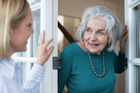 Stará pani otvára dvere návšteve - mladej pani a usmievajú sa na seba