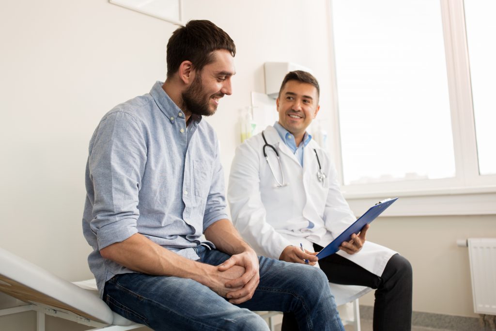doktor s pacientom sedia na lôžku a usmievajú sa nad výsledkami